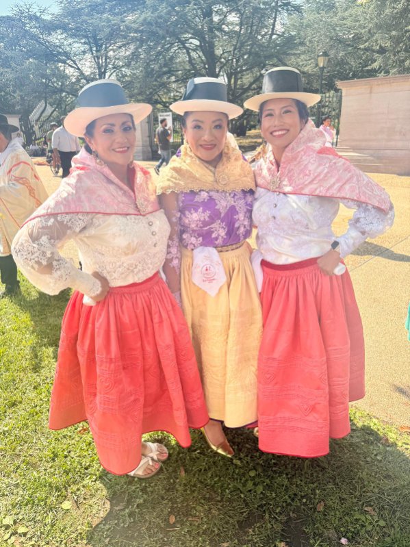 Three dancers in coral and pink traditional costumes