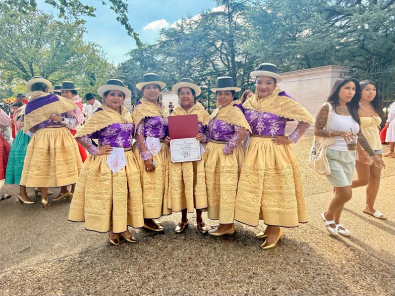 Dancers in gold and purple costumes with certificate